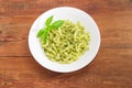 Cooked spiral pasta with sauce pesto on white dish