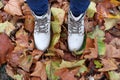 Top view of white female shoes on colorful pile of autumn leaves
