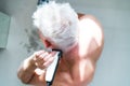 Top view white hair man doing self haircut with a clipper and looks in the mirror. Self-care at home in the conditions Royalty Free Stock Photo