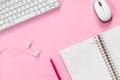 Top view of white home office desk with laptop, notebook, headphones and computer mouse on pink paper background Royalty Free Stock Photo