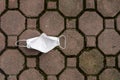 Top view of a white KN95 mask littered on a sidewalk. Backside of face mask