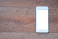 Top view of white mobile smartphone with blank white screen display for mockup on brown wooden table background. Royalty Free Stock Photo