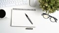 Top view of white office desk with notebook, glasses, house plant, coffee cup and pen. Royalty Free Stock Photo