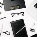 Top view white office desk table. Flat lay workspace with eye glasses, laptop, smartphone, clipboard, notebook and a pen