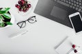 Top view of office table with laptop, notebook, smartphone, glasses, plant and snack. Having cherries while working.