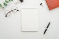 Top view of white office desktop with blank spiral notepad, glasses, supplies and leather wallet. Mock up Royalty Free Stock Photo