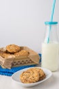 Top view of white plate with chocolate chip cookies, bottle of milk with blue straw, metal box with cookies and blue wool cloth, o Royalty Free Stock Photo