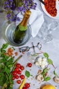 Top view of a gray table with plate, champagne, tomatoes, asparagus, glasses, corkscrew, beans on a gray background. Royalty Free Stock Photo