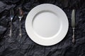 Top view of white plate with vintage cutlery on black background Royalty Free Stock Photo