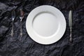 Top view of white plate with vintage cutlery on black background Royalty Free Stock Photo