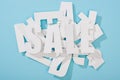 Top view of white sale word on pile of letters on blue background.