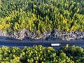 Top view at white semitrailer truck driving between rock tunnel in autumn forest of Karelia, Russia