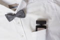 Top view of white shirt and bow tie, male perfume in the pocket.Classic accessories