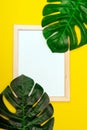 Top view of a white square frame mockup with palm leaf decoration. Summer composition on yellow background Royalty Free Stock Photo