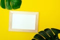 Top view of a white square frame mockup with palm leaf decoration. Summer composition on yellow background Royalty Free Stock Photo