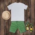 White t-shirt with green shorts, sandals, hat placed on the wooden floor Royalty Free Stock Photo