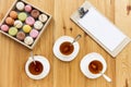 top view of white tea cups, tasty macarons in box and blank paper sheet