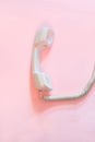 Top view of white telephone handset, receiver and cord isolated on pink. Royalty Free Stock Photo