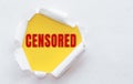 Top view of white torn paper and the text CENSORED on a yellow background