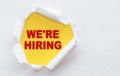 Top view of white torn paper and the text - WE`RE HIRING on a yellow background