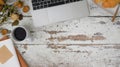 Top view of white vintage workspace with laptop, coffee cup, notebook, dry rose and   croissant on wooden table Royalty Free Stock Photo