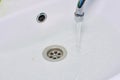 Top view of a white washbasin in the bathroom with a tap from which water flows. The concept of blockage, water consumption, Royalty Free Stock Photo