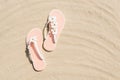 Top view of white woman flip flops with flowers on sandy beach. Summer vacation concept on a sunny day Royalty Free Stock Photo