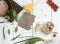 Top view on a white wooden table with the ingredients of the dish, vegetables, tomatoes, green peas, onions, a basket of garlic,