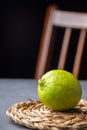 Top view of a whole lime on rope stand, defocused chair and black background