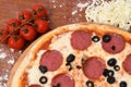 Top view of a whole pepperoni pizza with olives on a wooden board on the table Royalty Free Stock Photo