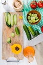 top view of whole sliced and cut cucumbers and black pepper on cutting board with tomatoes bowl of cucumber slices and cucumbers