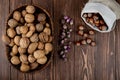 top view of whole walnuts in a wicker basket and hazelnuts scattered from a sack on wooden background Royalty Free Stock Photo