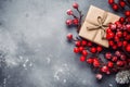 Top view of a winter composition of gift box kraft and juicy red rowan berries, on a textured gray background. Christmas copyspace