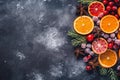 Top view of a winter composition of orangery citrus slices, red berries, Christmas tree branches and spices, on a textured gray