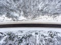 Top view at wintry slippery highway passing through snow covered coniferous forest in mountains Royalty Free Stock Photo