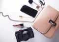 Top view of woman beige bag with accessories smartphone, cosmetics, lasses, camera and perfume on white background. Royalty Free Stock Photo