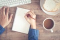 Top view of woman business hand writing the notebook and using computer on desk and have coffee, toast on the wooden table