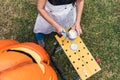 Woman dipping a paintbrush into can to paint a polystyrene pumpkin outdoors