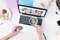 top view of woman drinking coffee with macaroon while using laptop