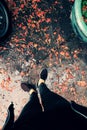 Woman feet in black clothes stand with orange petals fall in raining day
