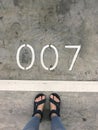 Top view of woman feet on concrete floor with number seven 007. Royalty Free Stock Photo