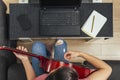 Top view of a woman giving online guitar lessons at home with her laptop.