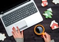 Top view of woman hand holding cup of hot coffee and working on open laptop, copy space. Christmas background with laptop. Royalty Free Stock Photo