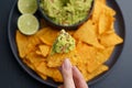 Top view of woman hand holding tortilla chips or nachos with tasty guacamole dip Royalty Free Stock Photo