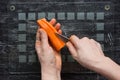 Top view of woman hands carving along raw carrot using knife to make decorative slices on the black background