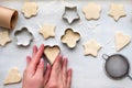 Top view of woman hands cooking a gingerbread cookie in the form of heart, star, cloud and flower. Christmas and New