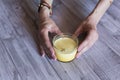 Top view of woman hands holding a glass with yellow juice. Grey wood tablet. Daytime. Healthy and lifestyle concept Royalty Free Stock Photo