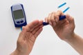 Top view of woman hands holding lancet and pricking finger to calculate blood glucose level on glucose meter