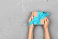 Top view woman hands holding present box with blue bow on gray background with copy space Royalty Free Stock Photo