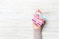 Top view woman hands holding present box with colored bow on white rustic wooden background with copy space Royalty Free Stock Photo